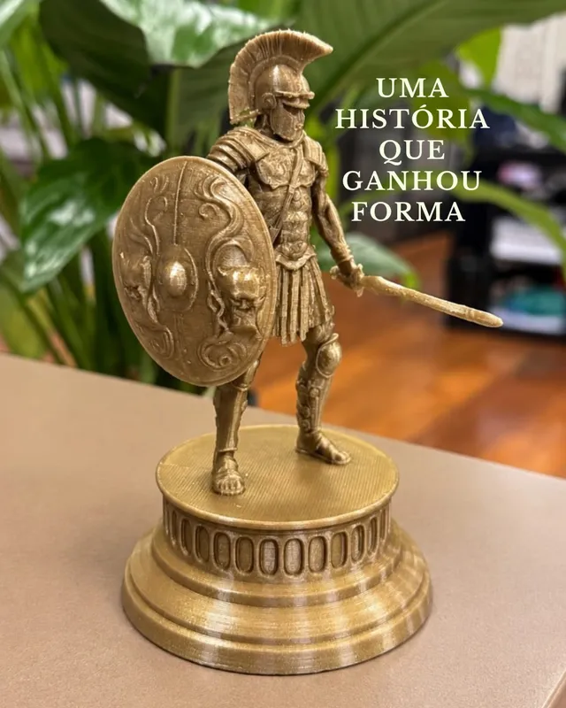Miniatura dourada de guerreiro romano com escudo e espada sobre pedestal