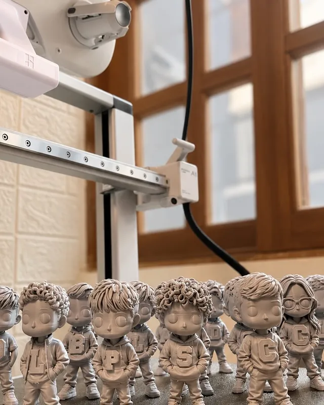 Várias miniaturas de pessoas, sem pintura, na mesa da impressora 3D